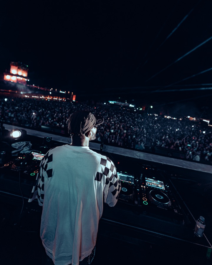 DJ performing to a large festival crowd at night